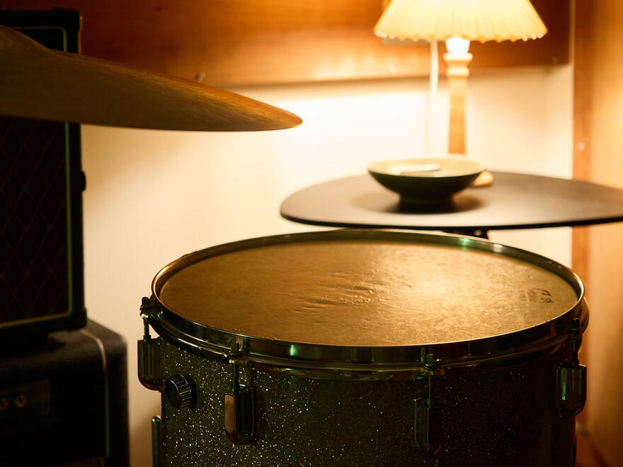 Close-up of a floor tom and cymbals beside a lamp in the live room. Close-up of a floor tom and cymbals beside a lamp in the live room.